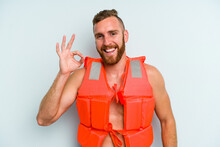 Young Caucasian Man Wearing Life Jacket Isolated On Blue Background Cheerful And Confident Showing Ok Gesture.