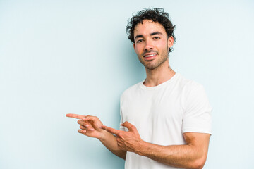 Young caucasian man isolated on blue background excited pointing with forefingers away.