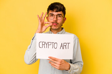 Wall Mural - Young hispanic man holding crypto art placard isolated on yellow background with fingers on lips keeping a secret.