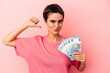 © Asier - Young caucasian woman holding banknotes isolated on pink background feels proud and self confident, example to follow.