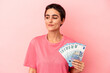 © Asier - Young caucasian woman holding banknotes isolated on pink background dreaming of achieving goals and purposes