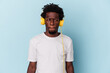 © Asier - Young african american man listening to music isolated on blue background confused, feels doubtful and unsure.