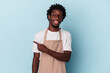 © Asier - Young african american store clerk isolated on blue background smiling and pointing aside, showing something at blank space.