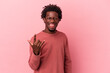 © Asier - Young african american man isolated on pink background showing rock gesture with fingers