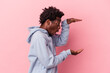 © Asier - Young african american man isolated on pink background shocked and amazed holding a copy space between hands.