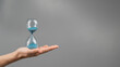© Михаил Решетников - Woman holding an hourglass on a gray background. Close-up. Copy space.