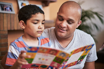 Sticker - Now its your turn to read. Cropped shot of a cheerful little boy and his father reading a storybook together at home during the day.