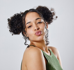 This is my favourite look. Shot of a woman with two buns posing against a grey background.