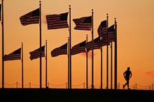 Lone Jogger And American Flags At Sunset.