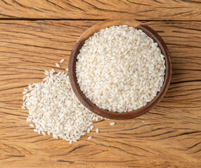 Raw carnaroli risotto rice in a bowl over wooden table