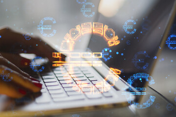 Close up of female hands using laptop keyboard with abstract glowing euro sign hologram on blurry background. Online banking, technology, data and finance concept. Double exposure.