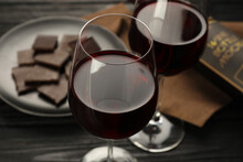 Tasty Red Wine And Chocolate On Black Wooden Table, Closeup