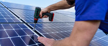 Man Worker Installing Solar Photovoltaic Panels On Roof, Alternative Energy Concept.Close Up Hands With Drill.