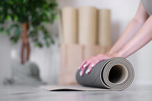 Close-up Of A Woman's Hands Rolling Up An Exercise Mat. Yoga Studio. Concept Of A Healthy Lifestyle.