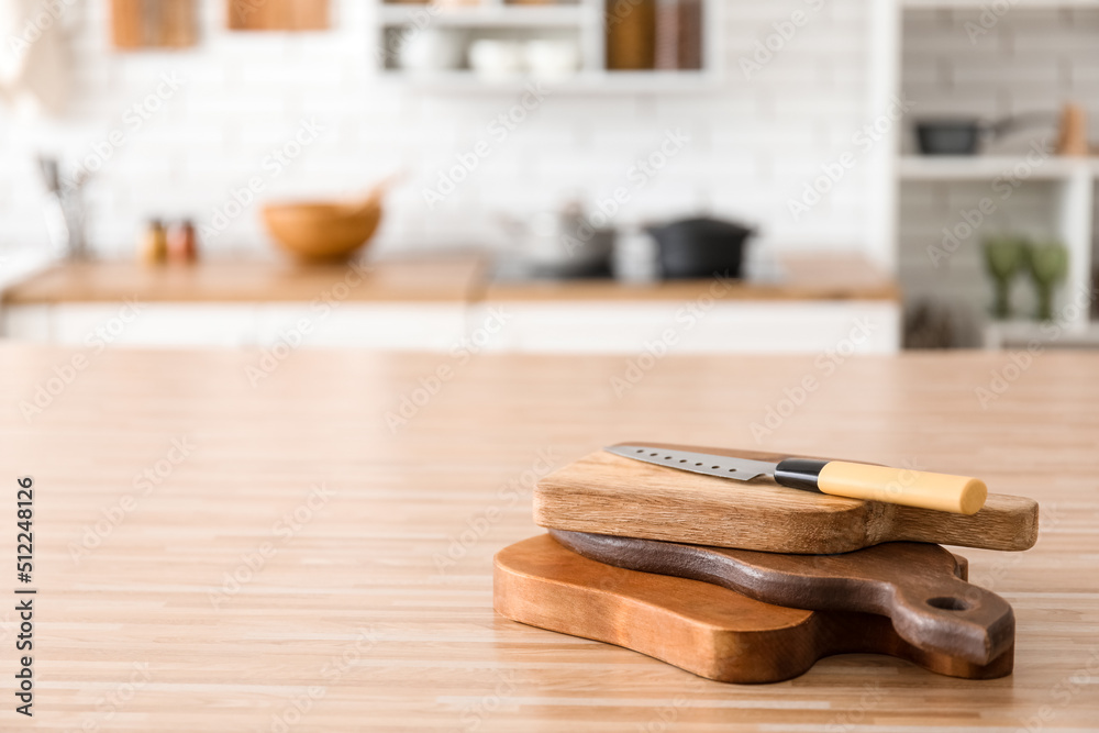 Stack of cutting boards and knife on wooden table in kitchen