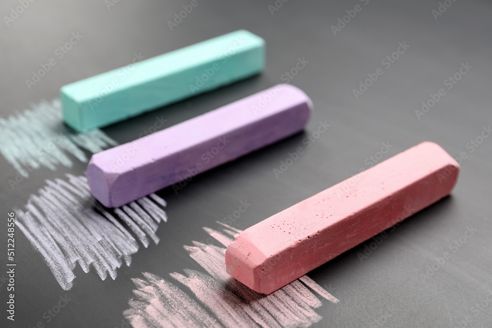 Colorful chalks on school blackboard, closeup