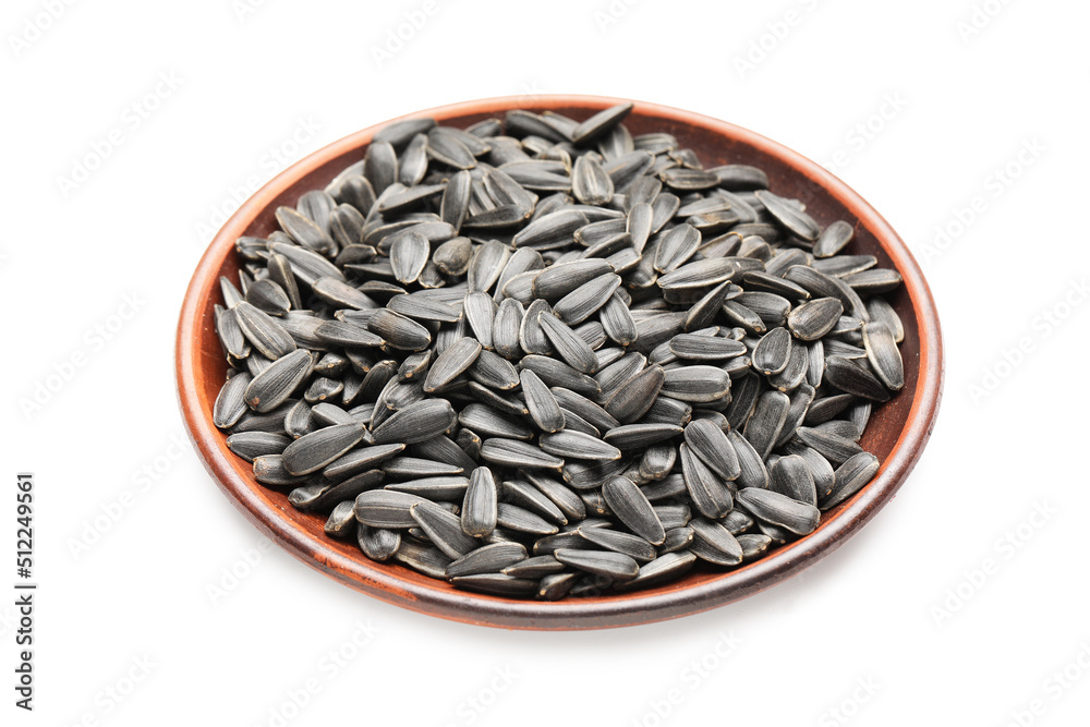 Plate with unpeeled sunflower seeds on white background