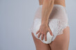 Rear view of a Woman in adult diapers on a white background. Incontinence problem. 