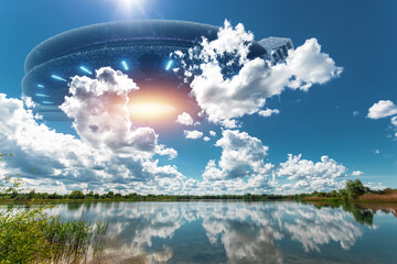 Wall Mural - ufo, an alien saucer hovering above the lake in the clouds, hovering motionless in the sky. unidenti
