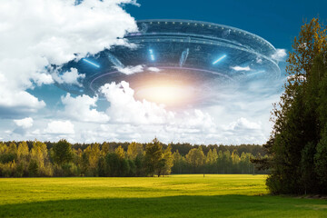 Wall Mural - ufo, an alien saucer hovering above the field in the clouds, hovering motionless in the sky. unident
