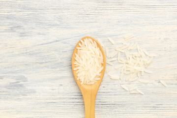 Wall Mural - Long Basmati rice in wooden spoon and bunch on white background, copy space. Macro. Flat lay. Diet and weight loss concept