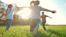 Kids Run In The Park. A Large Group Of A Team Of Children Running Back View Sunlight In The Summer On The Grass In Lifestyle The Park Camera Movement. People In The Park Happy Family Kid Dream Concept
