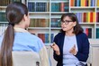 © Valerii Honcharuk - Female teacher talking to teenage student in the library