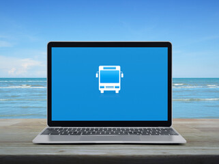 Bus flat icon on modern laptop computer monitor screen on wooden table over tropical sea and blue sky with white clouds, Business transportation online service concept