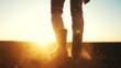 © maxximmm - farmer feet walks across a black field. agriculture business concept. silhouette of a farmer feet at sunset walking across a black plowed field. farmer in rubber boots legs lifestyle close-up