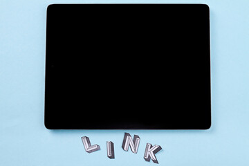 Tablet pc with link word on blue background. Top view flat lay.