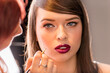 Make-up Artist Retouching the Bourgundy Red Lipstick on the Full Natural Lips of a Beautiful Caucasian Woman With Cat Blue Eyes and Open Mouth