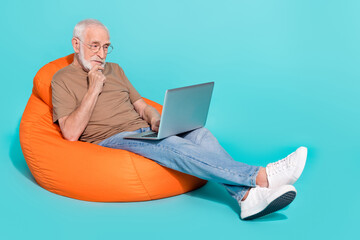 Sticker - Portrait of handsome trendy focused grey-haired man using laptop studying isolated over bright blue color background