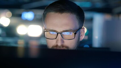 Close-up of a concentrated man in glasses who works at a computer.