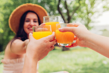 Crop women clinking glasses of juice in park