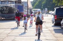 Active Family Cycling On The City Summer Shore Street.