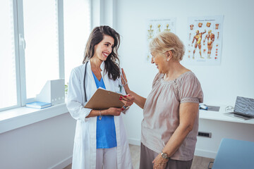 Smiling female patient at consultation with woman doctor. Patient Having Consultation With Doctor In Office. Cropped shot of a medical practitioner reassuring a patient