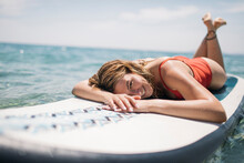 Smiling Woman Enjoys Sunbathing On Paddle Board