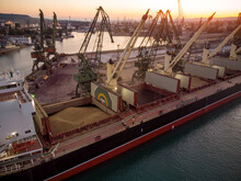 Aerial View Of Big Cargo Ship Bulk Carrier Is Loaded With Grain Of Wheat In Port At Sunset