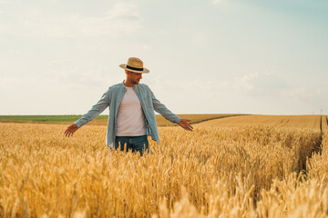Wall Mural - Happy farmer is standing in his growing wheat field.