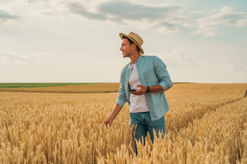 Poster - Happy farmer using mobile phone while standing in his growing  wheat field.	