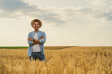 Wall Mural - Happy farmer is standing in his growing wheat field.