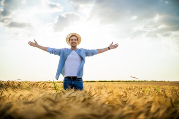 Wall Mural - Happy farmer with arms outstretched standing in his growing barley field.