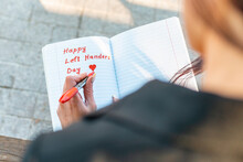 Woman Writes In A Notebook, Holds Felt-tip Pen In Her Left Hand.Outdoors Summer Evening Park. Left-handers Day August 13th.Closeup.