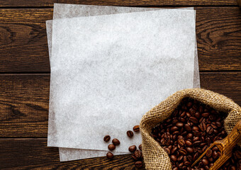 Wall Mural - Coffee beans in sack, white paper copy space over wooden background