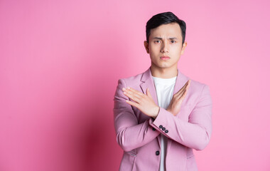 Wall Mural - Portrait of young Asian man wearing pink suit posing on background