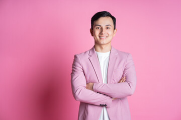 Portrait of young Asian man wearing pink suit posing on background