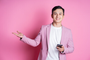 Wall Mural - Portrait of young Asian man wearing pink suit posing on background