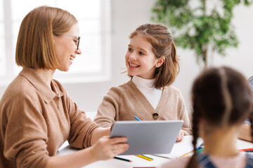 Wall Mural - Woman with tablet teaching children at school