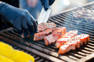 Wall Mural - Cooking BBQ Fish. Gloved hands turn pieces of fish on the grill. Grilled salmon on a charcoal grill. Picnic in the backyard during a family holiday.