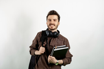 Wall Mural - Cheerful caucasian man wearing brown shirt posing isolated over white background student with books and backpack and looking at the camera. High school university college concept.